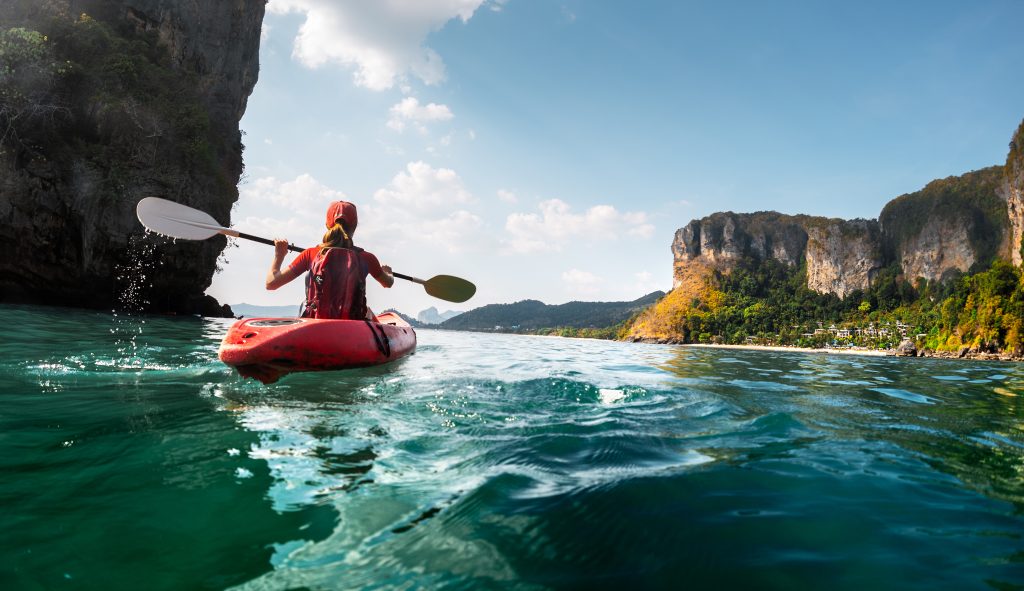 Lady paddling the kayak in the calm tropical bay