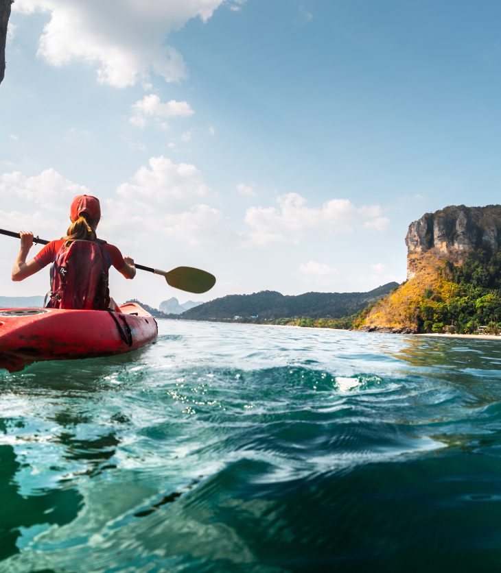 Lady paddling the kayak in the calm tropical bay